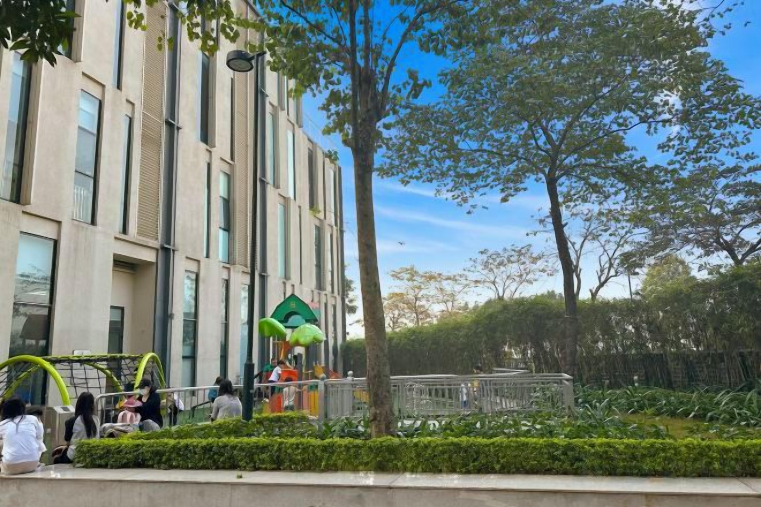 A building with a modern design, a well-maintained garden, and a clear sky.