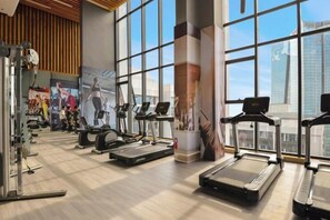 Une salle de sport équipée de tapis de course, de vélos elliptiques et d'appareils de musculation.