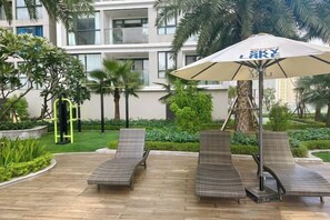 Un patio de hotel con sillones de descanso y una sombrilla grande.