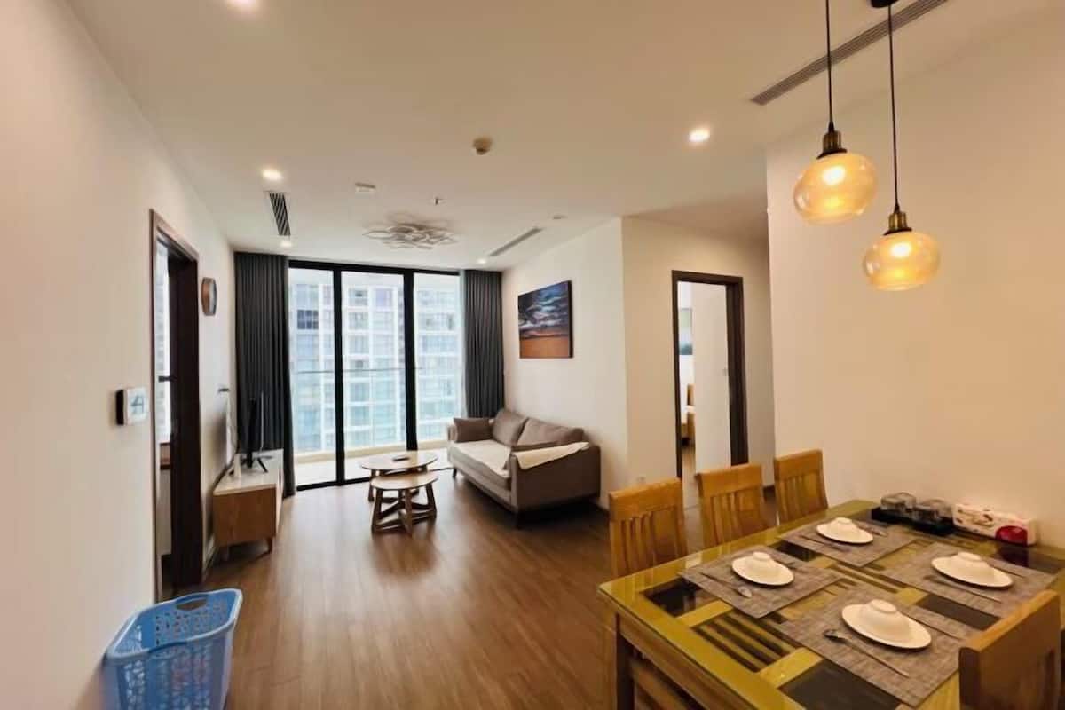 Un salon moderne avec un canapé, une table à manger et des chaises. Une grande fenêtre offre une vue sur la ville.