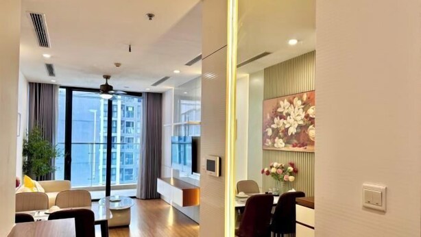 A modern hotel room with a dining area, large windows, and a ceiling fan. - Vinhomes Skylake by TA Home – Premium Hanoi Apartment (Hanoi)