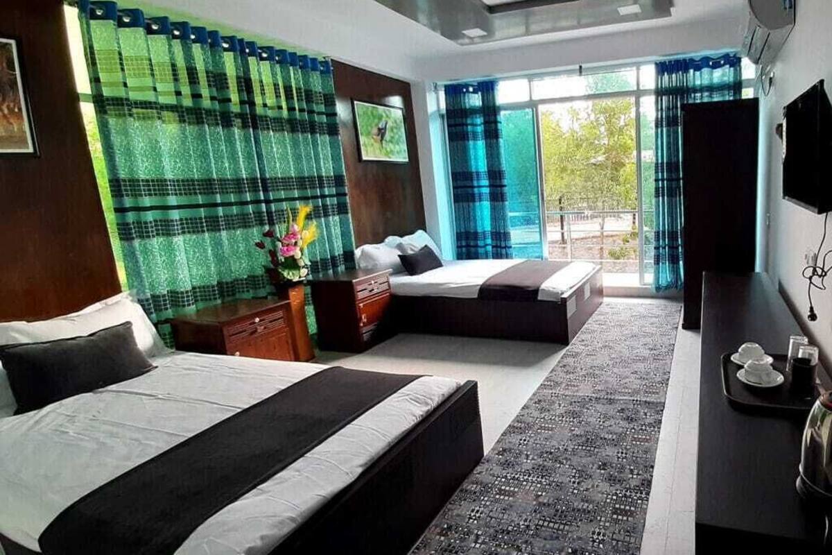 Ett hotellrum med två sängar, ett skrivbord, en TV och en balkong med utsikt.