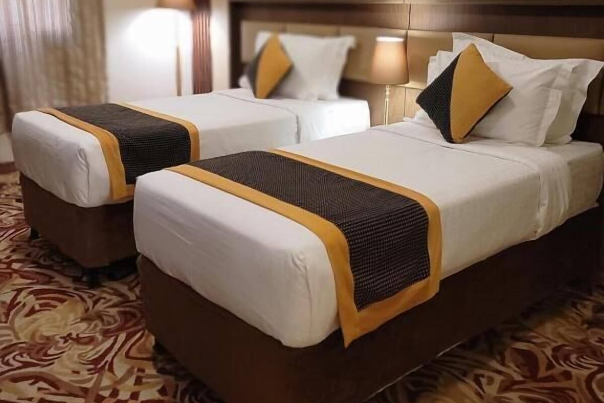 A hotel room with two beds, a patterned carpet, and a wooden headboard.