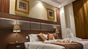 Ein Hotelzimmer mit einem großen Bett, zwei Nachttischlampen, einer Kopfteil und zwei gerahmten Bildern an der Wand.