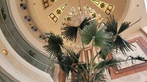Ein prachtvoller Atrium mit einer zentralen Säule, einem Chandelier und einem kreisförmigen Deckenmuster.