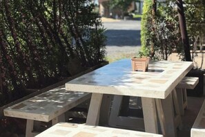 A concrete picnic table with benches, surrounded by greenery. - Skyinn Resort (Khok Samrong)