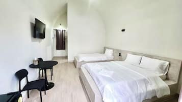 A bedroom with a bed, a desk, two chairs, a TV, and a shower area.