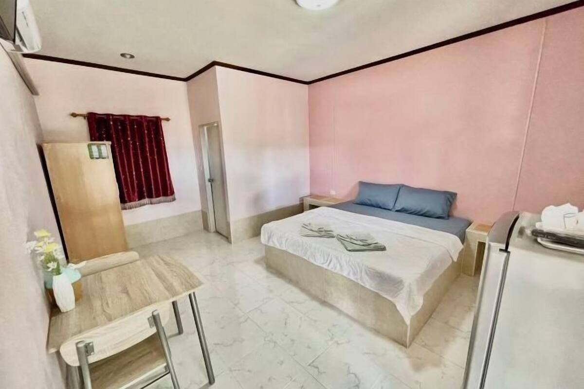 Ein Hotelzimmer mit Bett, kleinem Tisch, Stuhl, Kleiderschrank und Bad.