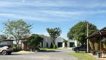 A residential area with houses, a gravel driveway, and parked cars.