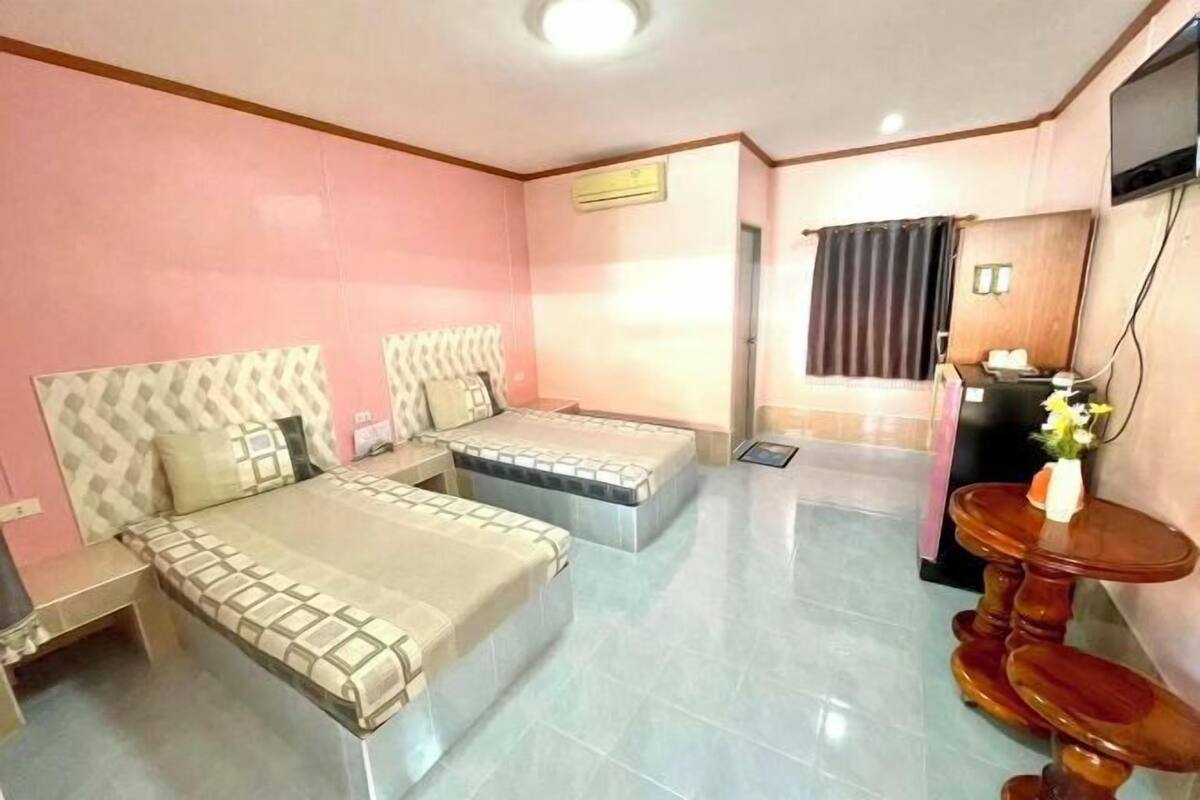 Ein Hotelzimmer mit einem Bett, einem Schreibtisch, einem Sessel, einem Fernseher und einem kleinen Tisch mit Blumen.