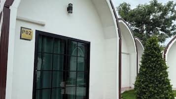 A building with a large glass door, a sign indicating room number P02, and a small green bush in front.