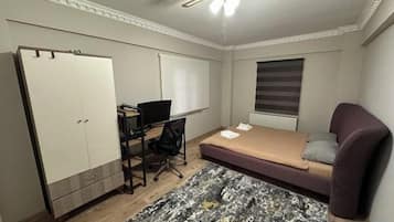 Un dormitorio con cama, escritorio, armario y ventilador de techo.