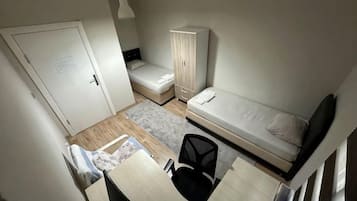 Una habitación pequeña con cama, escritorio, silla y armario.