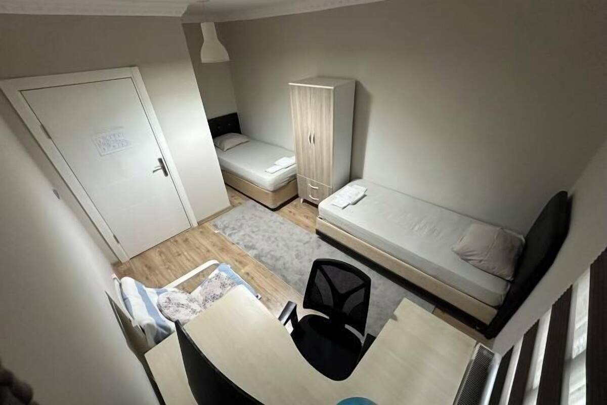 Une petite pièce comprenant un lit, un bureau avec une chaise, une armoire et une porte.
