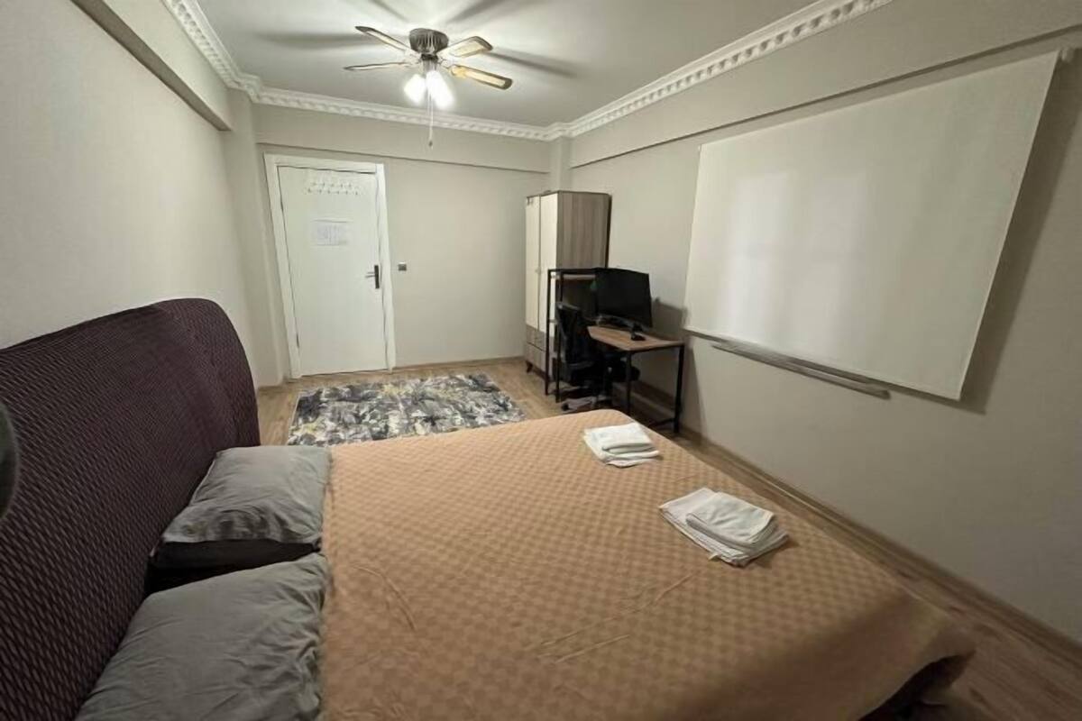 Une chambre à coucher avec un lit, un ventilateur de plafond, une armoire et un téléviseur.
