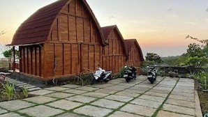 A rustic wooden barn with a stone-paved driveway and parked motorcycles. - Munduk Terrace By Zuzu (Munduk)