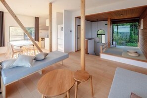 A modern interior with a wooden floor, a round table, a sofa, and a bench. - The Villas〜atami amazing ocean view〜 (Atami)