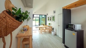 A modern kitchen with a refrigerator, microwave, wooden table, and chairs. - Baan Ga-cha (Chiang Rai)