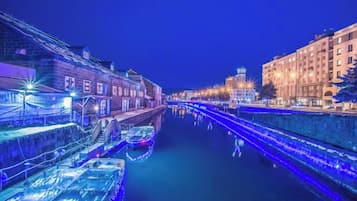 A nighttime view of a canal with illuminated buildings and a bridge.