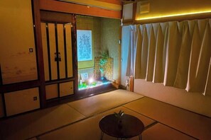 A traditional Japanese room with tatami flooring, a shoji screen, and a small table with a plant. - Otaru Retreat Come Inn (Otaru)