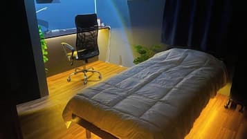 A room with a bed, a desk with a chair, and a view of the outdoors.