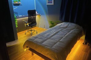 Una habitación con cama, escritorio y silla, y vistas al exterior.