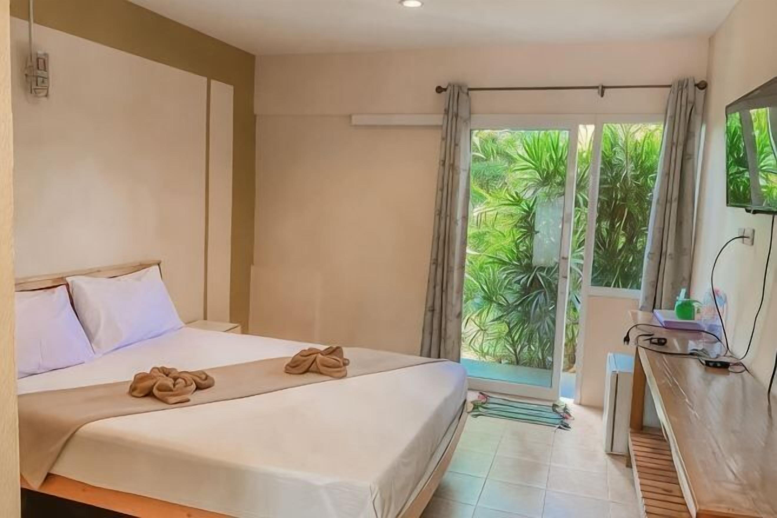 Ein Hotelzimmer mit Bett, Schreibtisch und Blick ins Grüne.