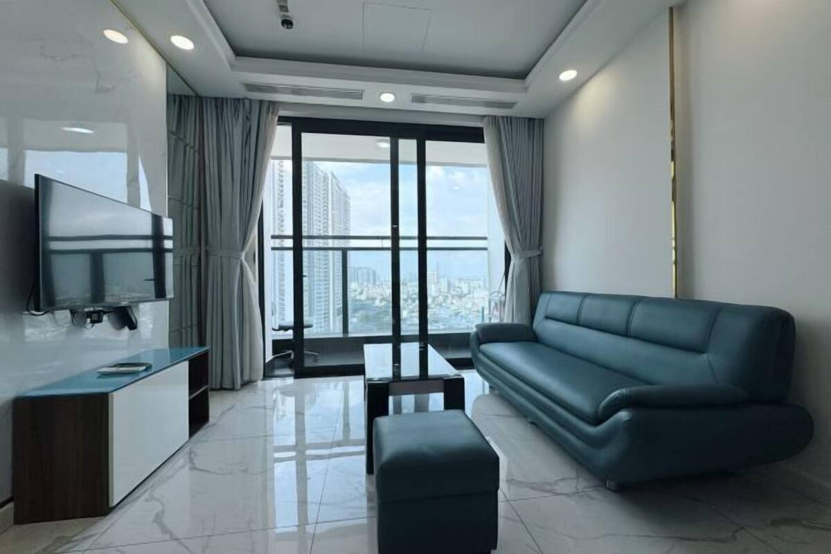 Ein modernes Wohnzimmer mit Flachbildfernseher, Sofa, Couchtisch und Balkon mit Stadtblick.