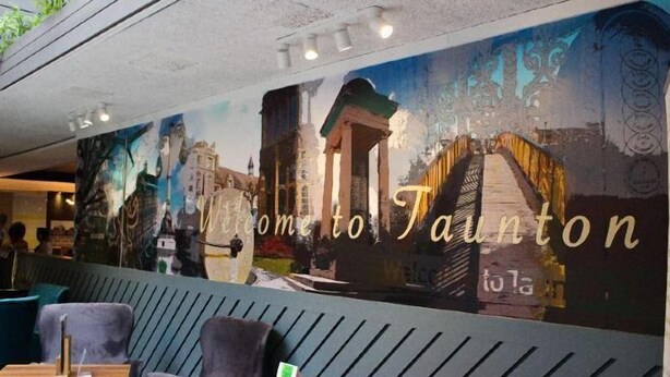 A restaurant interior with a mural of a cityscape and the text "Welcome to Taunton." - Holiday Inn TAUNTON M5, JCT.25 by IHG (Taunton Deane District)