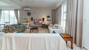 A living room with a sofa, a coffee table, a TV, and a ceiling fan. - d'Fun Desaru 16-20pax Private pool / BBQ / KTV (Bandar Penawar)