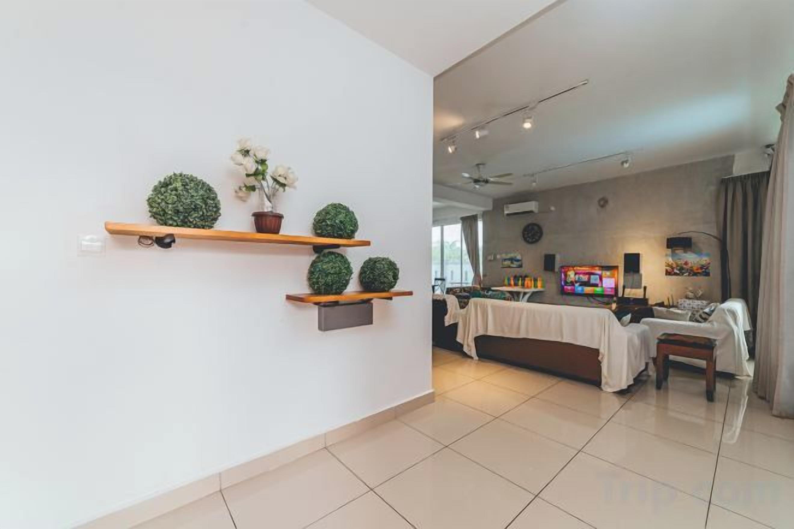 A modern living room with a sofa set, a coffee table, and a TV. There are shelves with decorative items on the wall.
