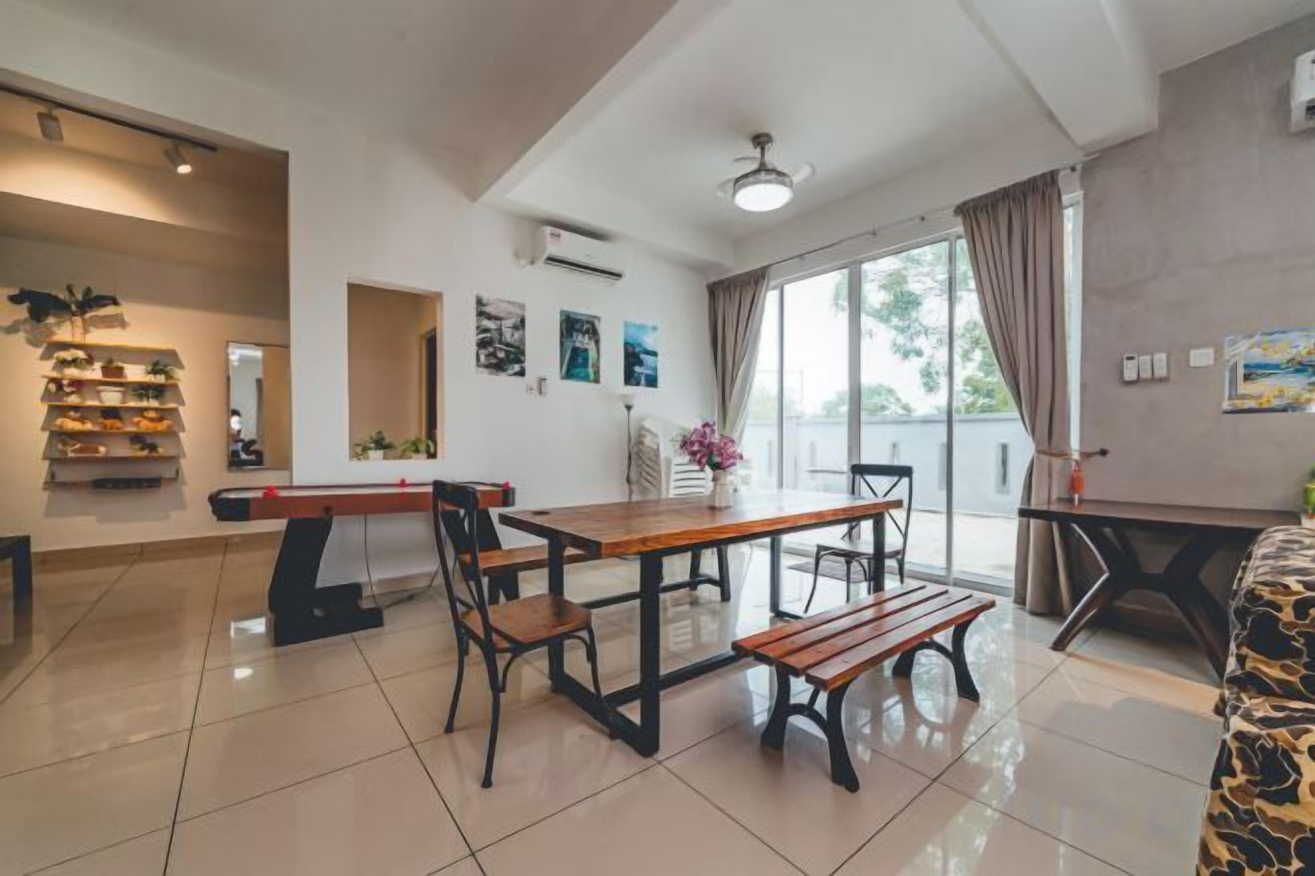 A spacious room with a dining table, chairs, a sofa, and a large window with curtains.