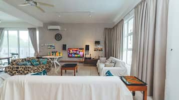 A living room with a sofa, a coffee table, a TV, and a ceiling fan.