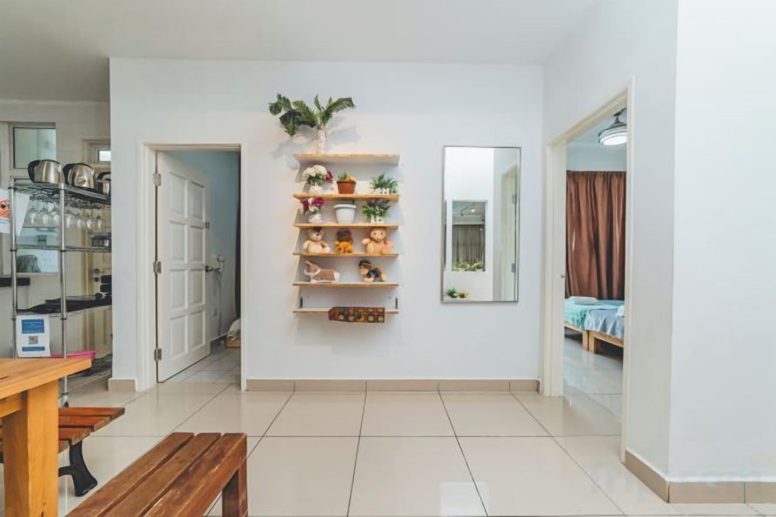 Un intérieur moderne avec un banc en bois, une étagère murale agrémentée d’objets décoratifs et une porte donnant sur une autre pièce.