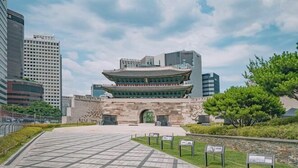 A traditional Korean building with a modern glass extension, surrounded by urban skyscrapers and a paved walkway. - QINGHE HOME (Seoul)
