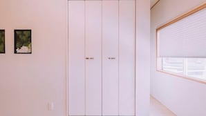 A room with a sliding door closet, a window with blinds, and two framed pictures on the wall. - “puff” Shinsaibashi Cloud House with Private Sauna (Osaka)