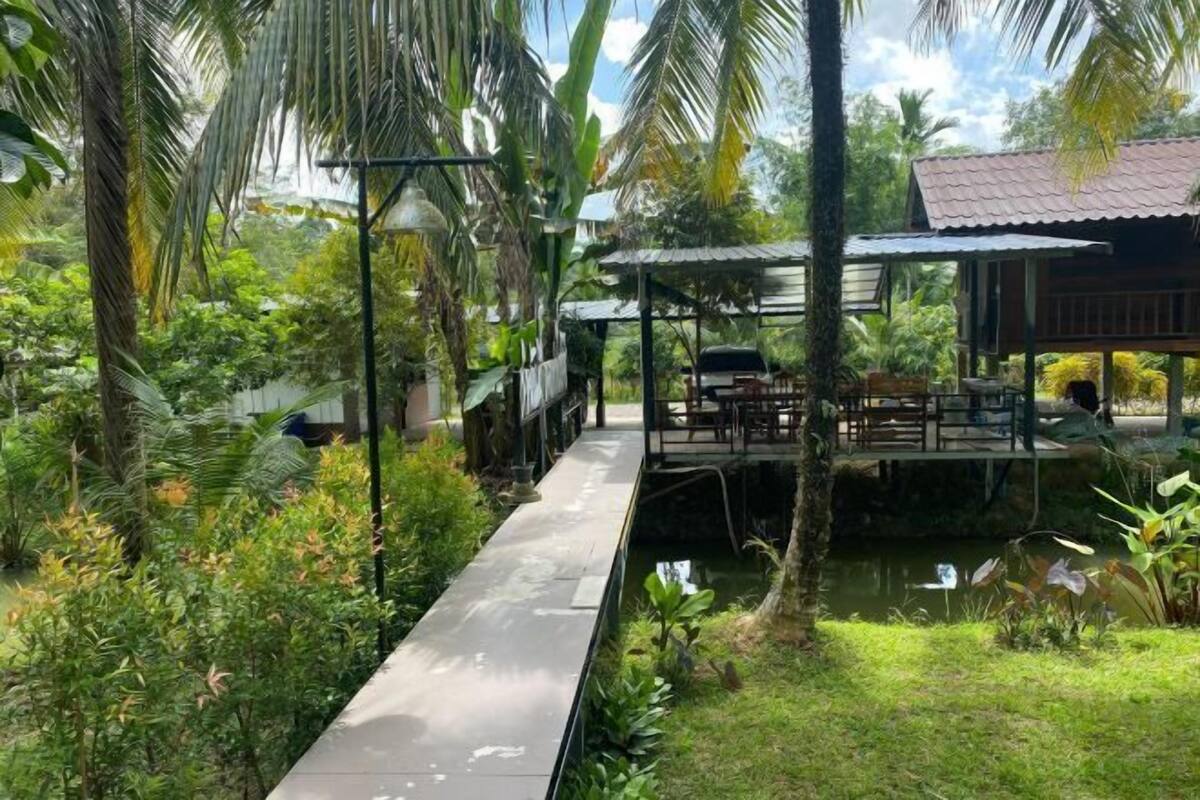 A wooden deck over water with a covered seating area and lush greenery.