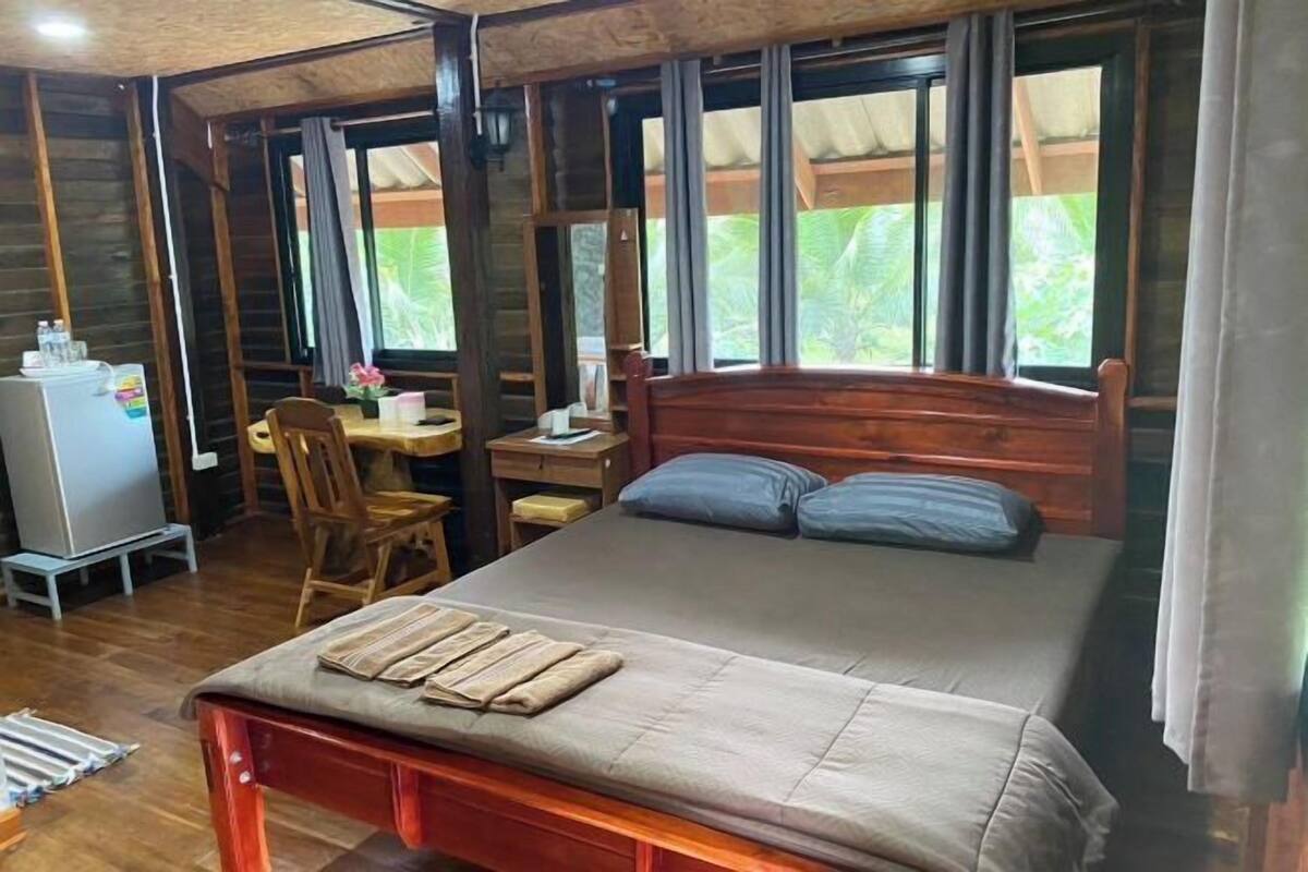 A wooden room with a bed, a desk, and a chair.