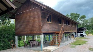 Una cabaña de madera con un porche cubierto y una escalera que lleva a un segundo nivel.