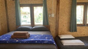 Una habitación con una cama, una cama más pequeña y un ventanal con cortinas.
