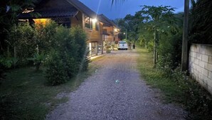 Una casa de madera con camino de grava, rodeada de abundante vegetación.