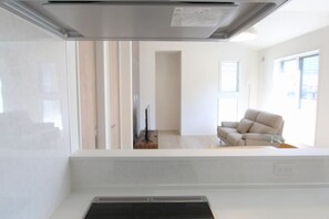 Une cuisine moderne dotée d’une hotte intégrée, d’un plan de travail blanc et d’une chaise beige en arrière-plan.