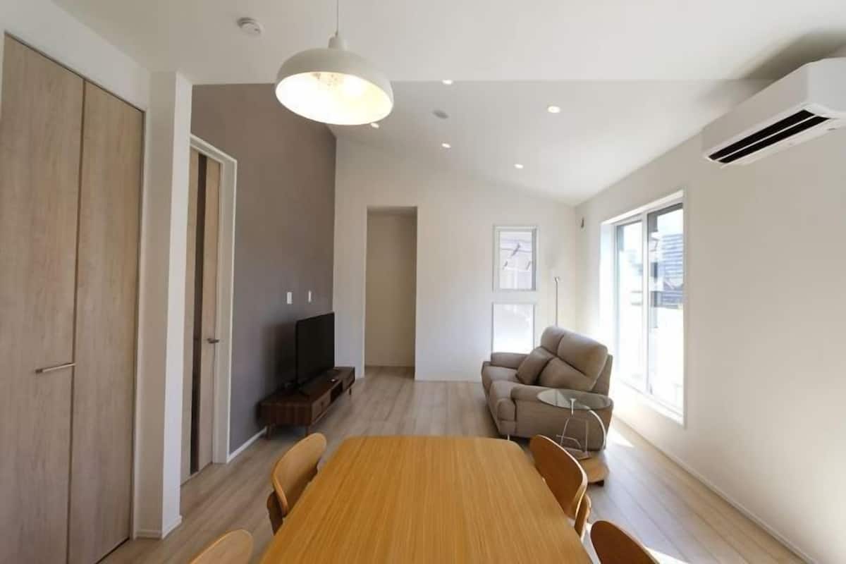 Una habitación amplia con una mesa de comedor de madera, un sofá y una televisión.