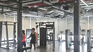 Un gimnasio con varios equipos de ejercicio, incluyendo máquinas de pesas y pesas libres.