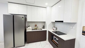 Una cocina moderna con armarios blancos, un refrigerador de acero inoxidable, un horno integrado y una encimera blanca.