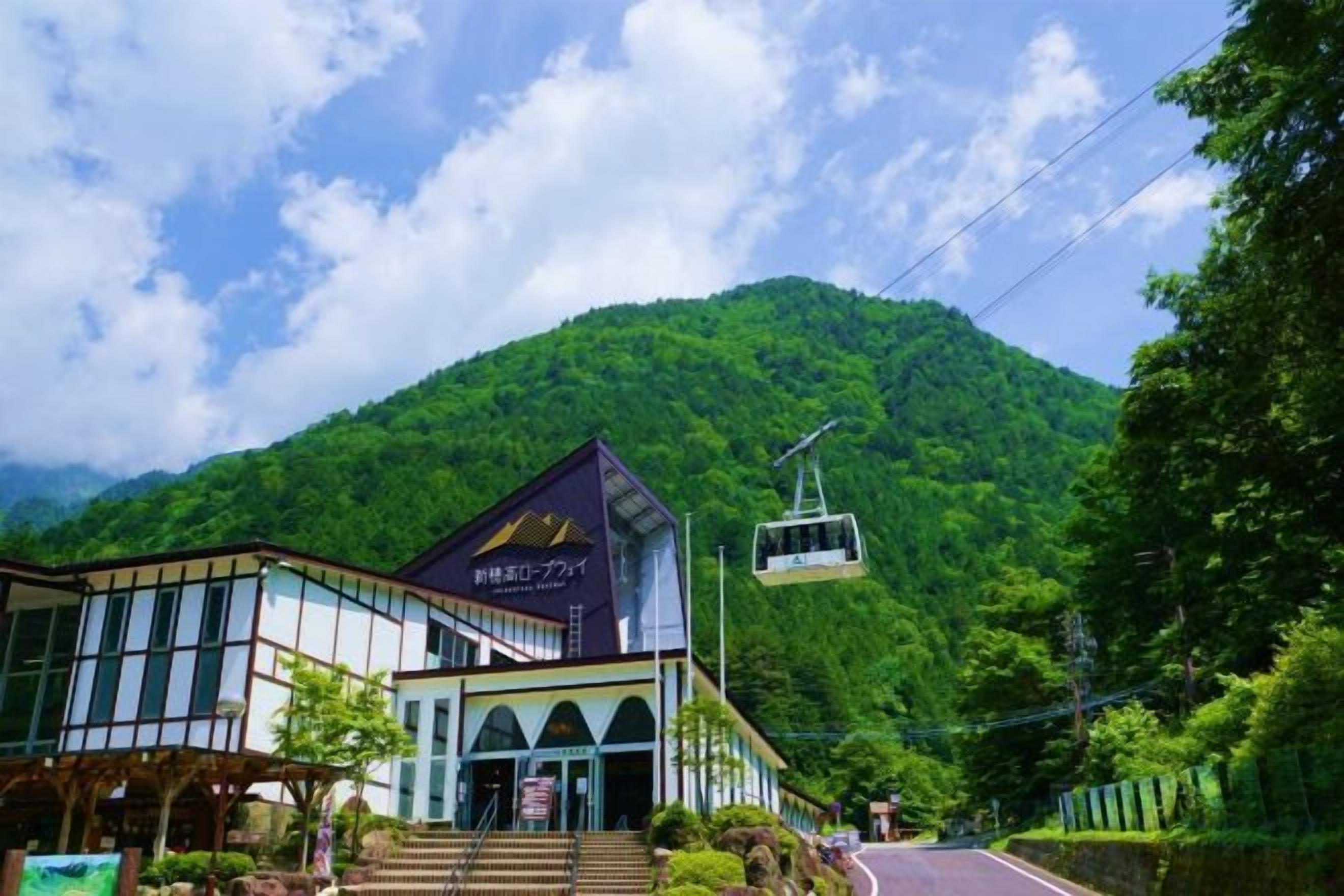 A building with a modern design, a signboard, and a cable car in the background.