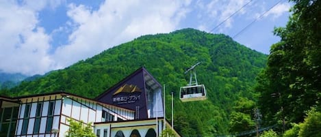 A building with a modern design, a signboard, and a cable car in the background.