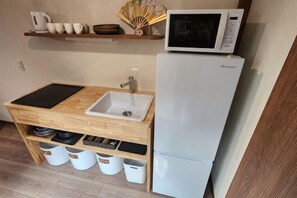 A compact kitchenette with a microwave, sink, and storage cabinets.