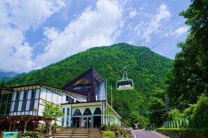 A building with a mountain backdrop, a lift, and a sign with Japanese characters.