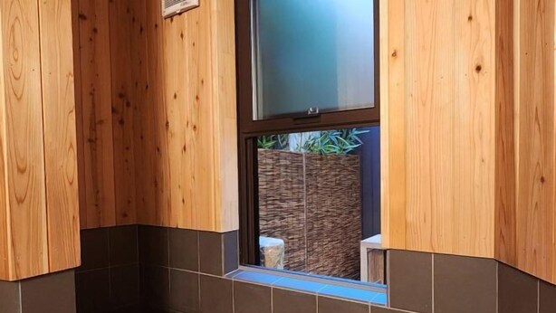 Un intérieur en bois avec une fenêtre, des murs carrelés et un espace extérieur visible, agrémenté de plantes.